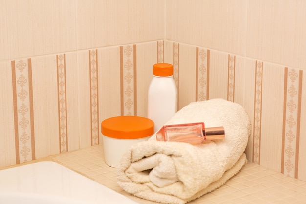 Shampoo, hair mask, body oil and bath towel in a bathroom. Space for text