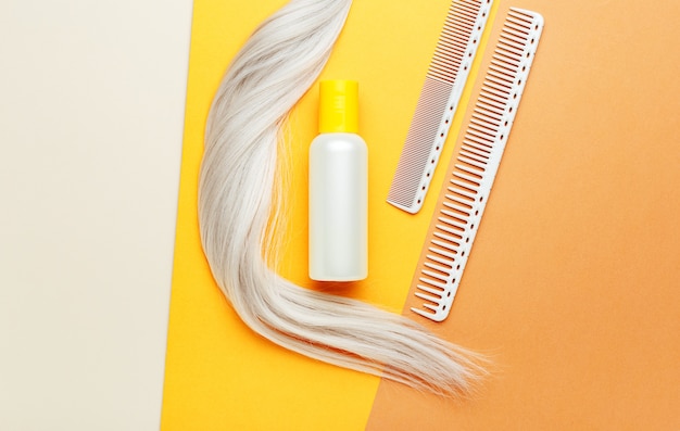 Shampoo oranje fles met lock curl van blond haar en kammen. kapperhulpmiddelen, kapsalonapparatuur voor het kappersvak