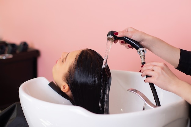 Shampoo wassen van vrouwelijk hoofd met lang donkerbruin haar in de kapsalon