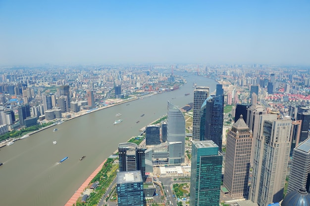 Shanghai city aerial view with urban architecture over river and blue sky in the day.