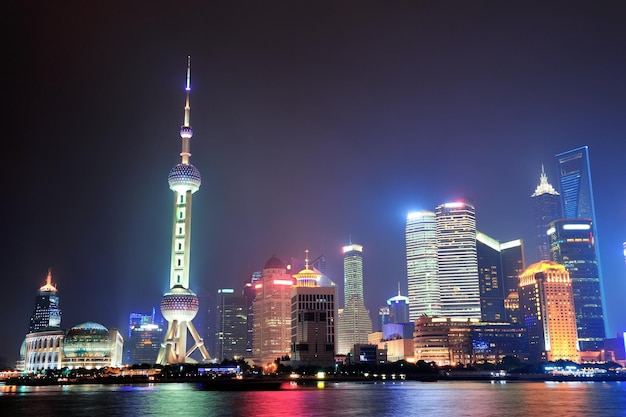 Shanghai night panorama over Huangpu River with skyline and urban buildings.