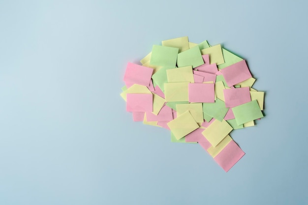 Foto forma del cervello umano rivestita con note di carta su sfondo blu concetto di salute mentale