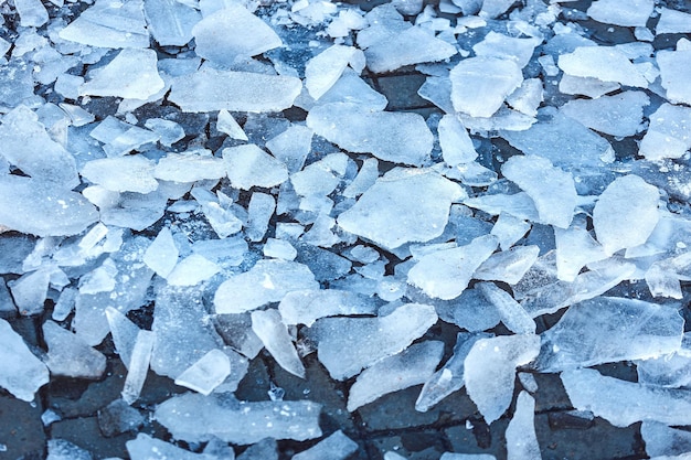 Shards of broken ice on sidewalk View from above Cleaning footpaths from icing