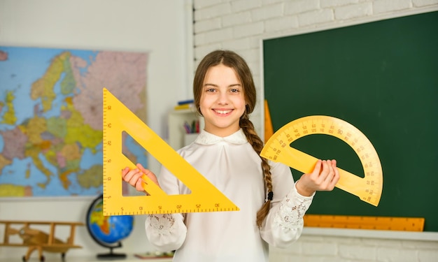Share quality educational content STEM concept Draw geometric figures Cute girl with rulers Favorite school subject Education and school concept Student learning geometry Kid school uniform