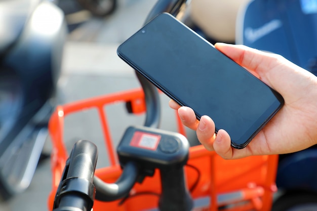 Фото Общие велосипеды. рука с помощью смартфона, сканирующего qr-код общего велосипеда в городе.