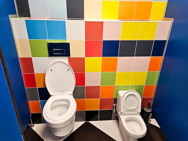 Foto bagno familiare condiviso luminoso con due tazze da bagno nel centro commerciale wc unisex per donna uomo mamma papà ragazzo ragazza bambino usare insieme bagno sala ricreativa per adulti bambino piccolo genitori grandi bambini cabina