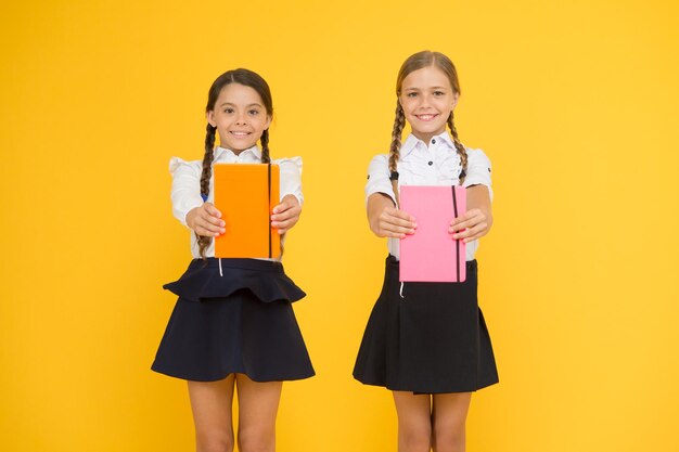 Photo sharing book love happy little girls holding books with colorful covers on yellow background cute small children smiling with encyclopedia or hand books educational books for pupils and students