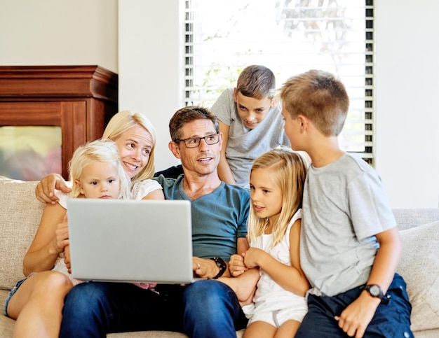 Sharing the digital world as a family Shot of a family using a laptop together at home