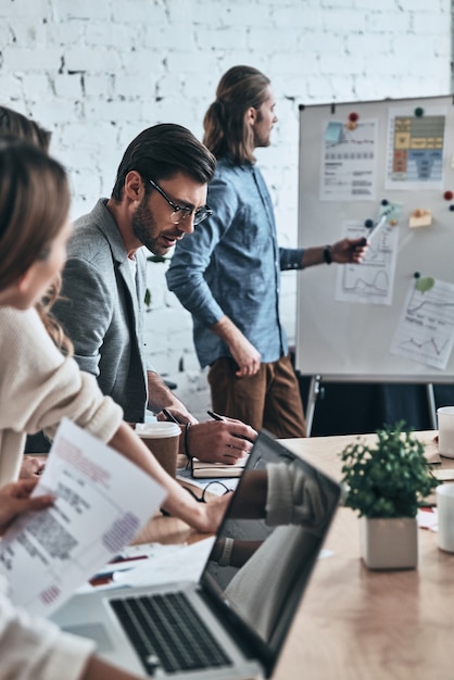 Photo sharing ideas. modern young man pointing at flipchart while conducting a presentation in the board room