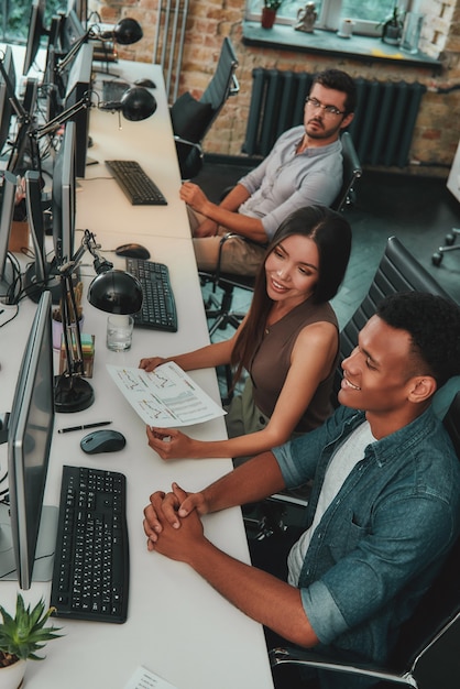 Foto condivisione di nuove idee vista dall'alto di un team multietnico che lavora su computer e comunica con