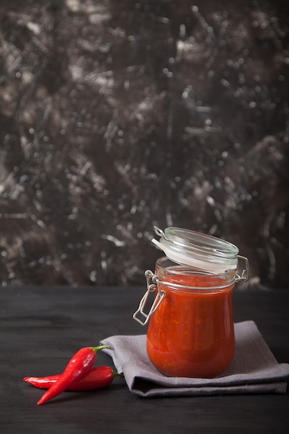 Sharissa spicy podpava in a glass jar and hot chili stands on a linen napkin. Traditional national cuisine. Copy spaes.