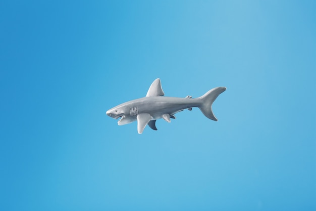 Giocattolo di squalo su sfondo blu con spazio libero.