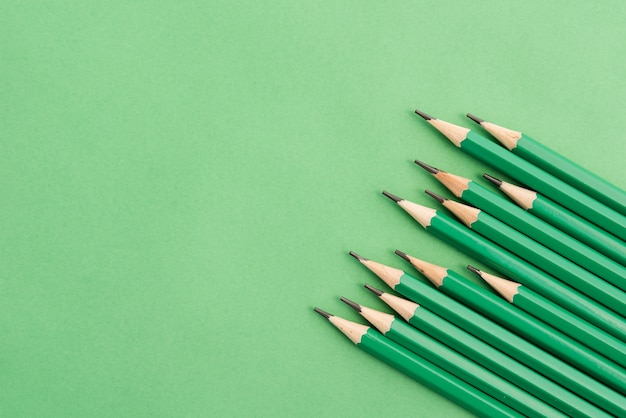 Sharp green pencil at the corner of plain background