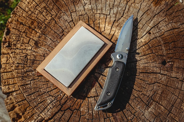 Sharp knife and grindstone on a wooden background