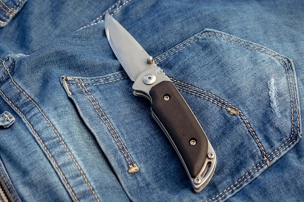 A sharp knife on a jeans background in nature