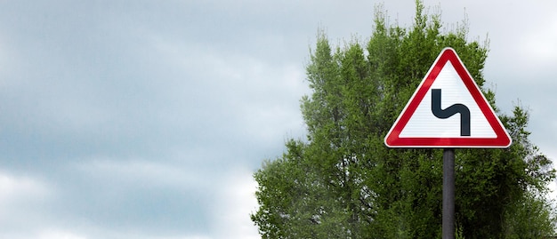 Sharp turn sign against the sky banner space for text