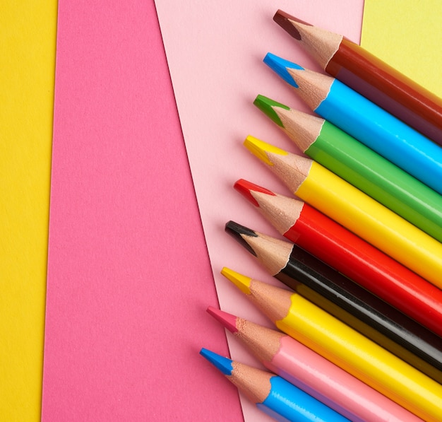 Sharpened colored wooden pencils on an abstract background of cardboard