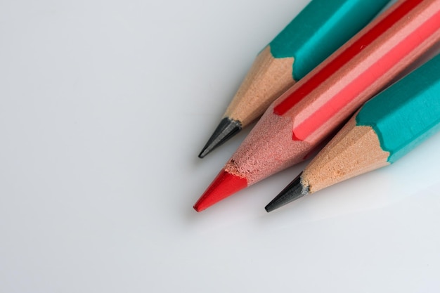 흰색 배경 클로즈업 매크로 사진에 가운데 연필 두 개와 빨간색 한 개를 날카롭게
