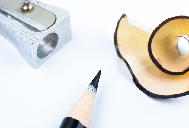 Sharpener and a broken pencil Shavings and a graphite on white background Close up Macro photo