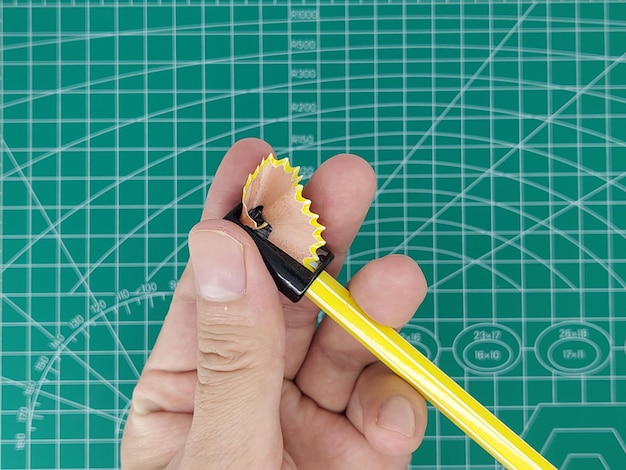 A sharpener is put on a pencil Wooden pencil shavings come out of the sharpener