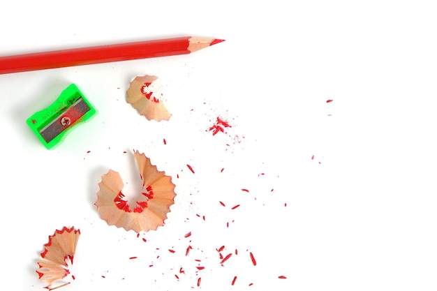 Sharpener and sharpened red pencil with sawdust on white background