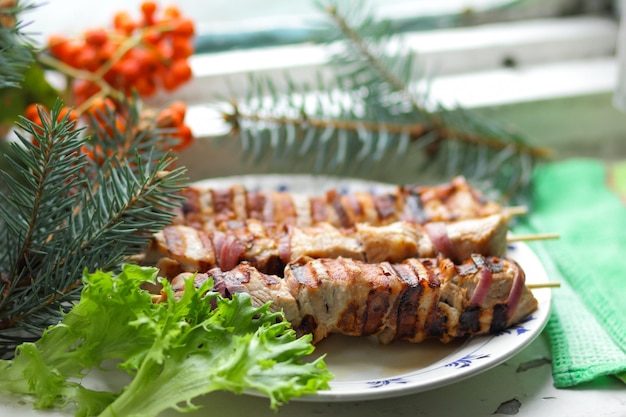 Shashlik met uien en kruiden met slabladeren op een onscherpe achtergrond Close-up van geroosterde shashlik op spiesjes