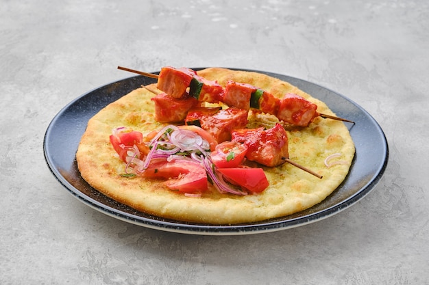 Foto shashlik servito su tortilla con pomodoro e cipolla rossa