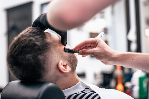 Radersi la barba nei barbercos. taglio di capelli da uomo e cura del viso. il barbiere fa un taglio di capelli al cliente.