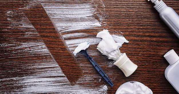 Shaving accessories on a wooden texture background. Tools. Disposable shaving machine, brush, foam and hazard razor.