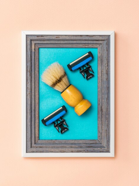 Shaving brush with two replaceable blades in a frame on a coral background. Collage. Minimalism. Modern creative creativity.