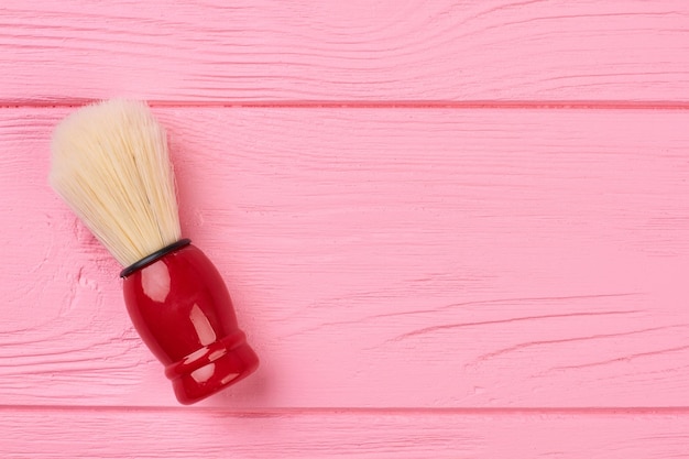 Pennello da barba su uno sfondo di legno. pennello da barba rosso vintage su tavolo di legno rosa, spazio per la copia. accessorio per l'igiene personale.