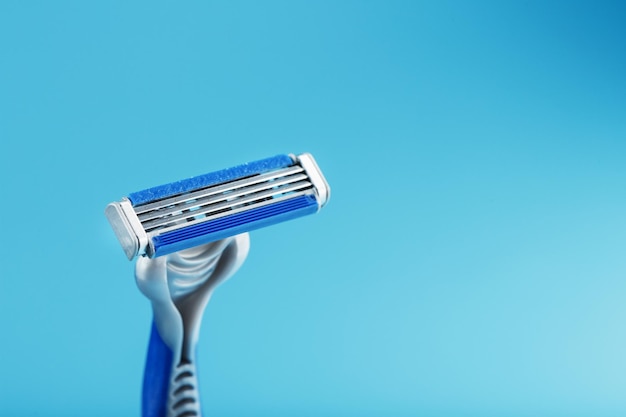 Shaving machine with three blades on a blue background closeup free space