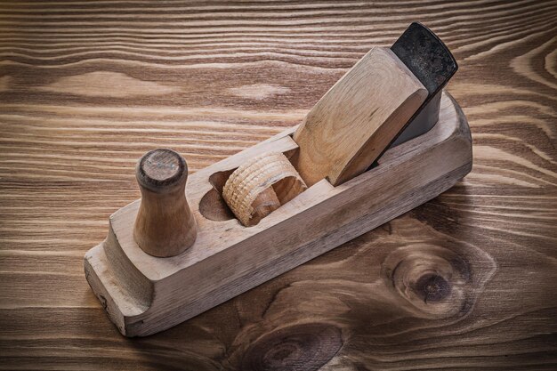 Shaving plane on vintage wooden board construction concept.