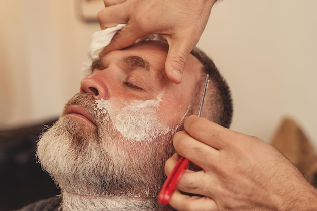 Shaving with a straight razor in a barbershop classic shave by\
stainless steel straight edge razor