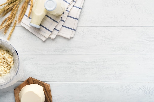 シャブオットユダヤ教の祝日お祝いミルクとチーズ熟した小麦とフルーツクリーム白い木製の背景上の乳製品白い木製の背景上の乳製品シャブオットのコンセプト上面図モックアップ