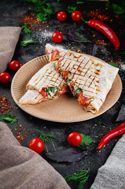 Shawarma pita pie ripiena di carne di pollo ed erbe aromatiche su un tavolo di pietra scura concetto di fast food e ristorante con consegna panino coperto