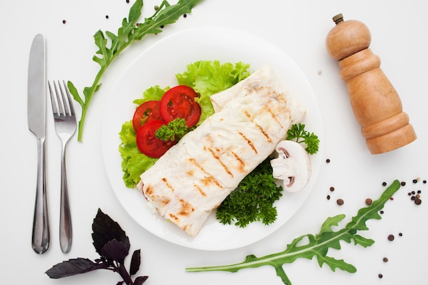 Shawarma on plate with cutlery and pepperbox