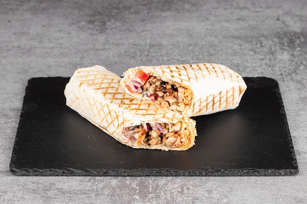 Photo shawarma roll in lavash with chicken fresh vegetables cream sauce and french fries on a wooden background selective focus