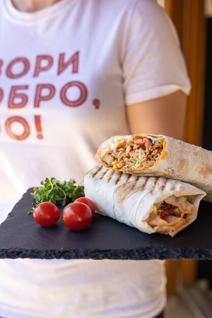 Shawarma with meat and vegetables on a black board