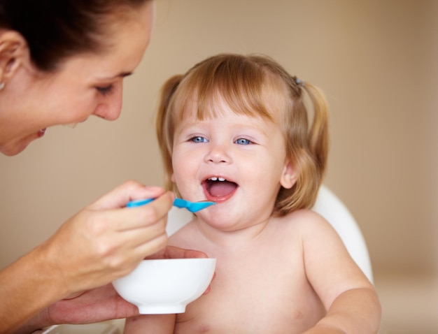 She enjoys being fed A cute little girl being fed by her mother