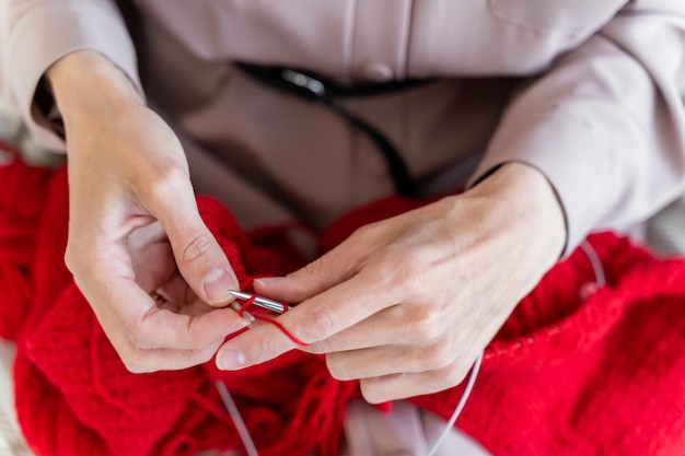 She is holding a pin and knitting with brown yarn Woman sitting in a chair