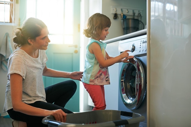 She knows which buttons to press Shot of a mother and daughter using a washing machine