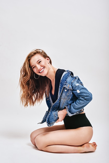 She laughs because she is happy seductive young lady in bodysuit and denim jacket looking