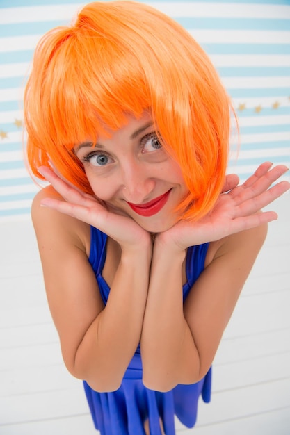 She likes bright outfit. Lady actress practicing performance. Girl posing striped background of studio. Lady red ginger wig posing in blue dress. Comic actress concept. Woman playful mood having fun.