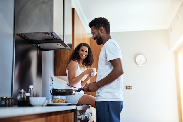 She loves watching him cook Cropped shot of a handsome young man cooking in the kitchen while his wife watches on