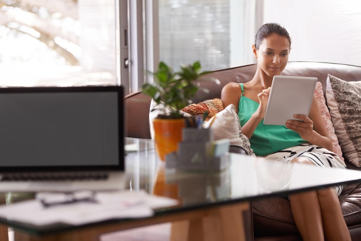 Photo she promised she wouldnt be distracted a beautiful young woman sitting on the couch using a digital tablet
