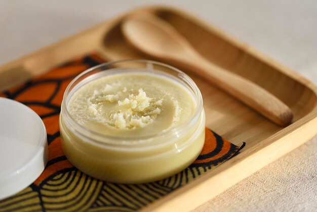 Shea boter pot geopend met zijn gegranuleerde textuur vergelijkbaar met boter van Afrikaanse oorsprong