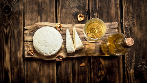 Sheep cheese with white wine and walnuts. On a wooden table.