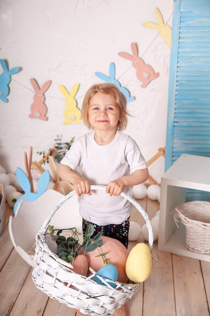 Sheerful girl with basket of colored eggs in her hands Funny crazy happy baby Easter to child