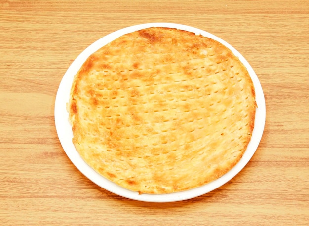 Sheermal taftan naan или kulcha roti подается в блюде, изолированном на деревянном столе, вид сбоку на индийскую пакистанскую еду